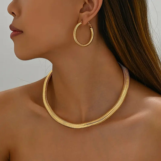 Gold hoop earrings and necklace on a model against a neutral background