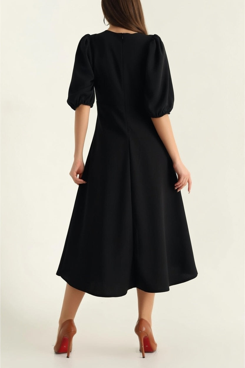 Woman wearing a black dress with puff sleeves on a white background