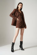 Woman wearing a brown outfit with black high-heeled boots on a white background