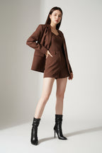 Woman wearing a brown outfit with black high-heeled boots on a white background