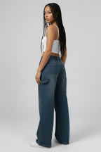 Woman wearing a white tank top and blue jeans on a gray background