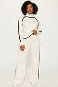 Person wearing a white outfit with black stripes on a plain background