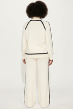 Person wearing a white outfit with black trim on a white background