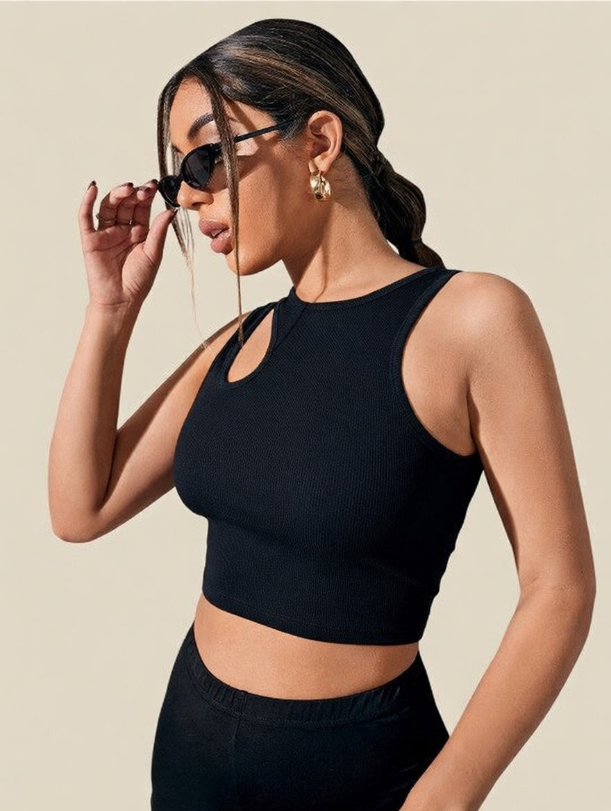 Woman wearing a black crop top and sunglasses against a beige background