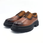 Brown leather shoes with black soles on a white background