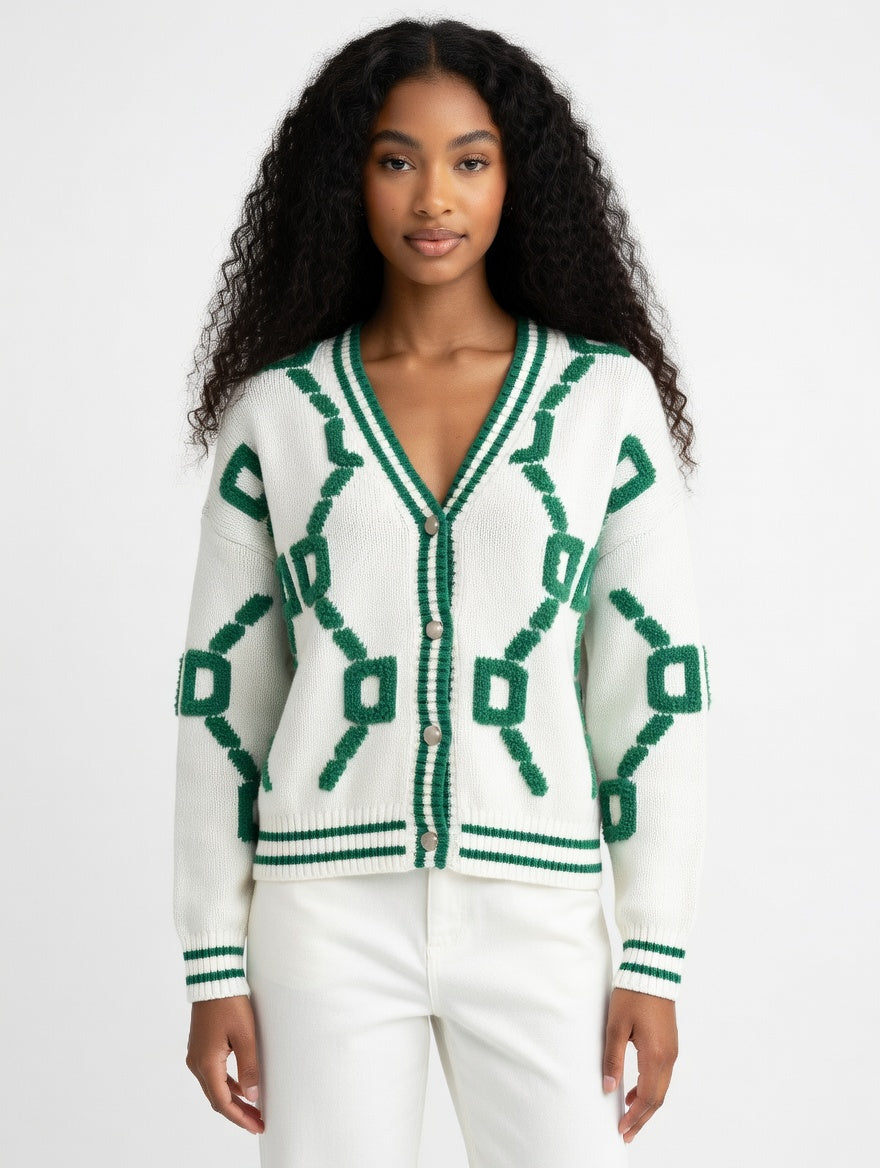Woman wearing a white cardigan with green geometric patterns on a plain background