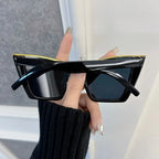 Black sunglasses held by a hand with a blurred background