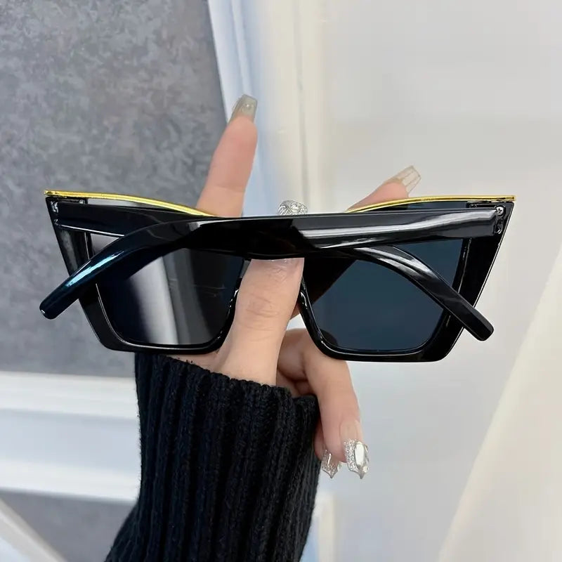 Black sunglasses held by a hand with a blurred background