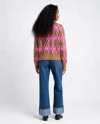 Person wearing a patterned sweater and blue jeans on a white background