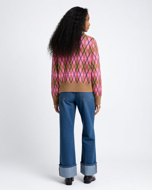 Person wearing a patterned sweater and blue jeans on a white background