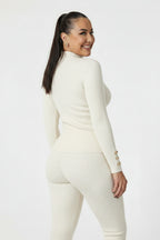 Woman wearing a white outfit with gold buttons on a white background