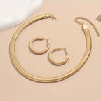 Gold necklace and hoop earrings on a beige surface