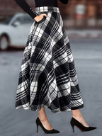 Person wearing a black and white plaid skirt with high heels on a blurred street background