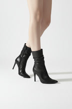 Black high-heeled boots worn with a neutral background