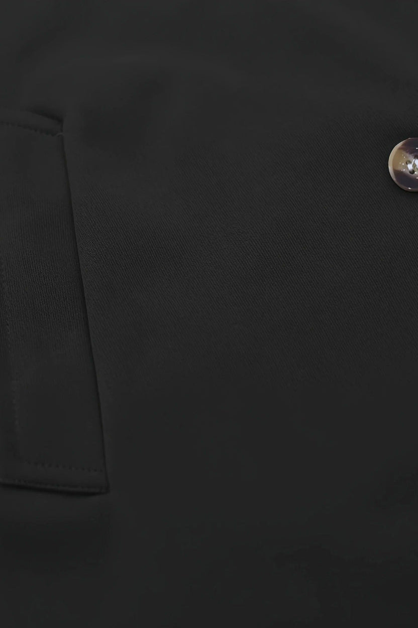 Close-up of a black jacket with a button on a dark background