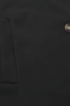 Close-up of a black jacket with a button on a dark background