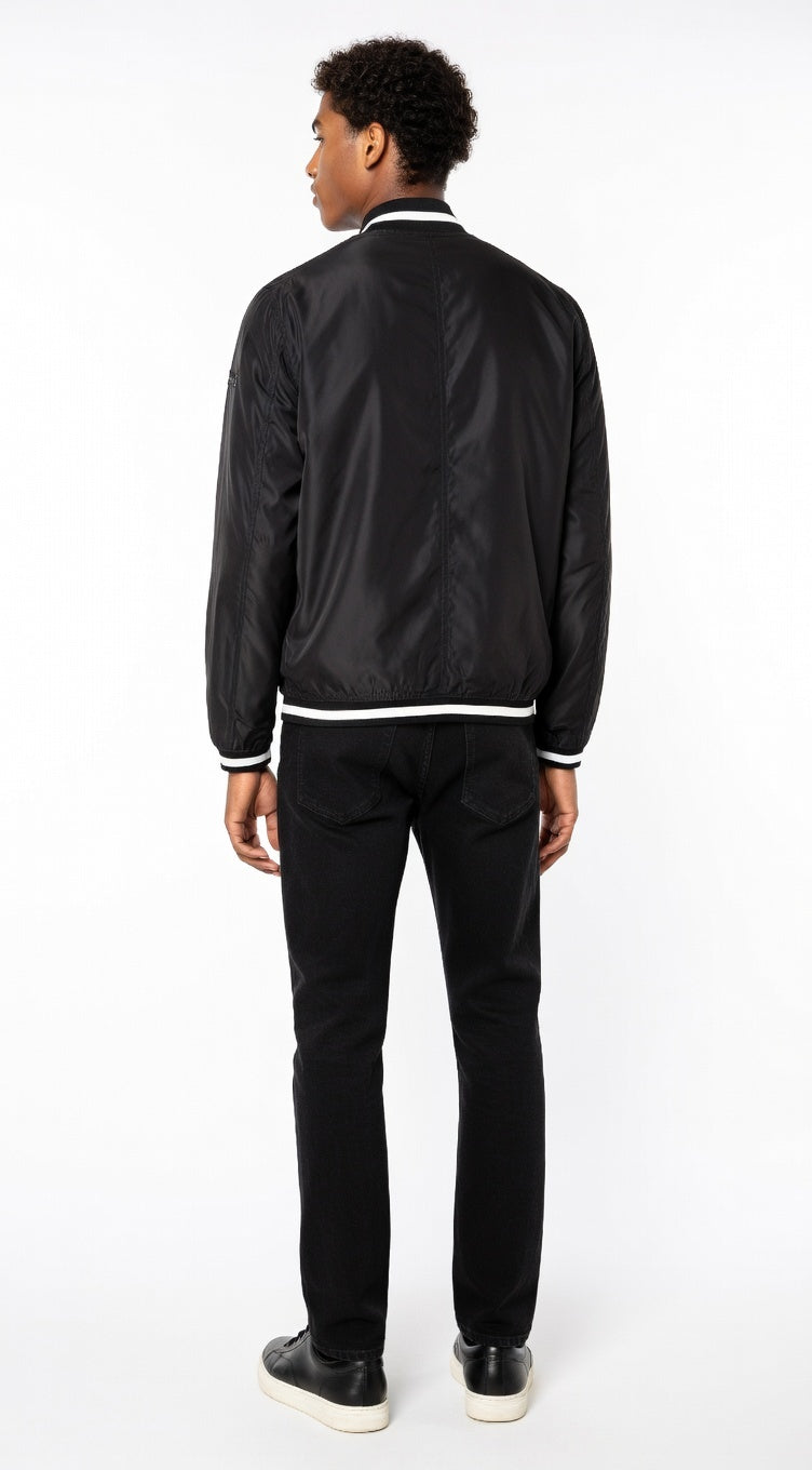 Person wearing a black bomber jacket and pants on a white background
