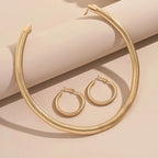 Gold necklace and hoop earrings on a beige background