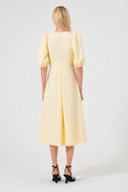Woman wearing a yellow dress with puff sleeves on a white background