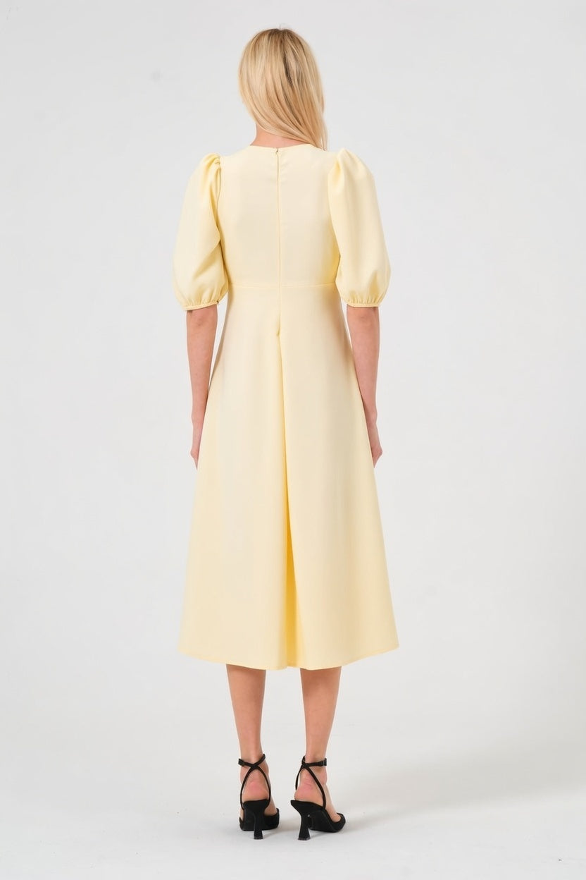 Woman wearing a yellow dress with puff sleeves on a white background