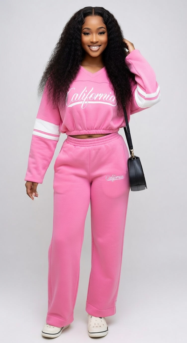 Person wearing a pink 'California' sweatshirt and pants set on a white background