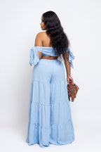 Woman wearing a light blue off-shoulder dress with ruffled sleeves on a white background