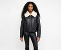 Woman wearing a black leather jacket with a white fur collar on a white background