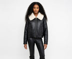 Woman wearing a black leather jacket with a white fur collar on a white background