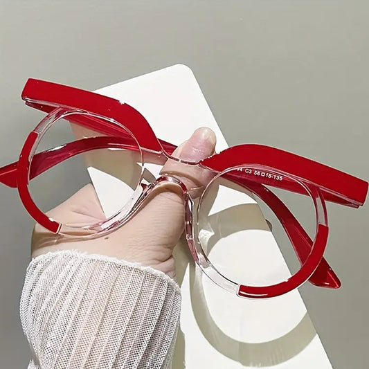 Red eyeglasses held by a hand against a neutral background