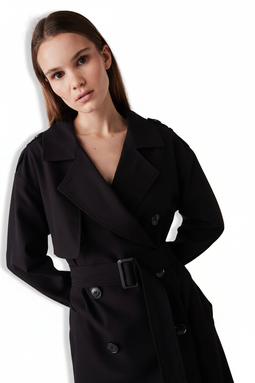 Woman wearing a black trench coat on a white background