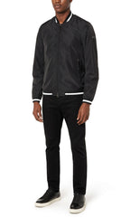 Man wearing a black bomber jacket and black pants on a white background