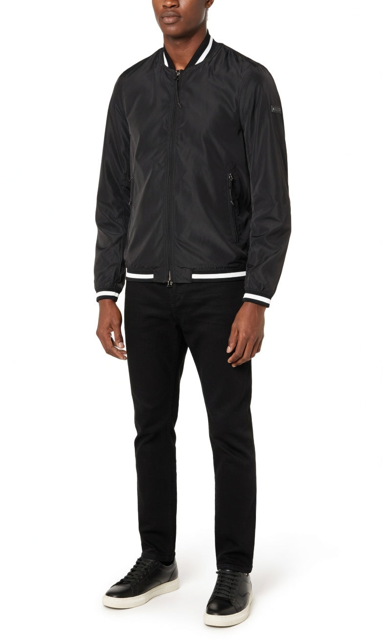 Man wearing a black bomber jacket and black pants on a white background