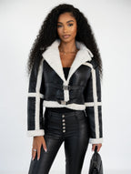 Woman wearing a black leather jacket with white fur trim on a white background