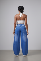 Person wearing a white top and blue denim wide-leg pants on a plain background