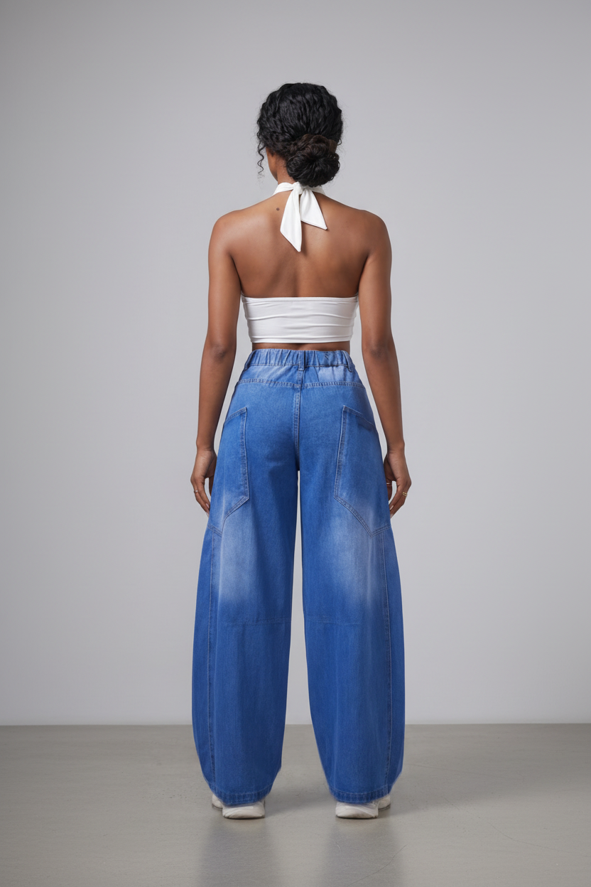 Person wearing a white top and blue denim wide-leg pants on a plain background