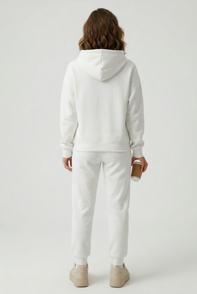 Person wearing a white hoodie and pants on a light gray background