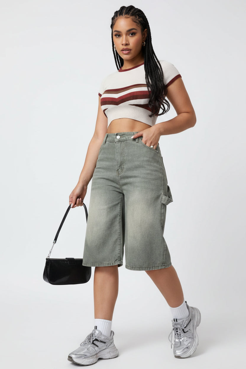 Person wearing high-waisted denim shorts with a plain background