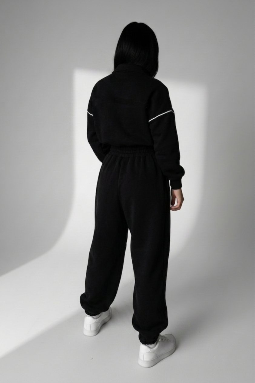 Person wearing a black tracksuit with white stripes on a white background