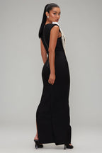 Woman wearing a black evening gown with pearl detailing on a gray background