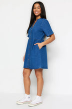 Woman wearing a blue denim dress against a white background