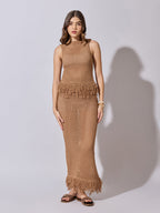 Woman wearing a brown crochet dress against a white background