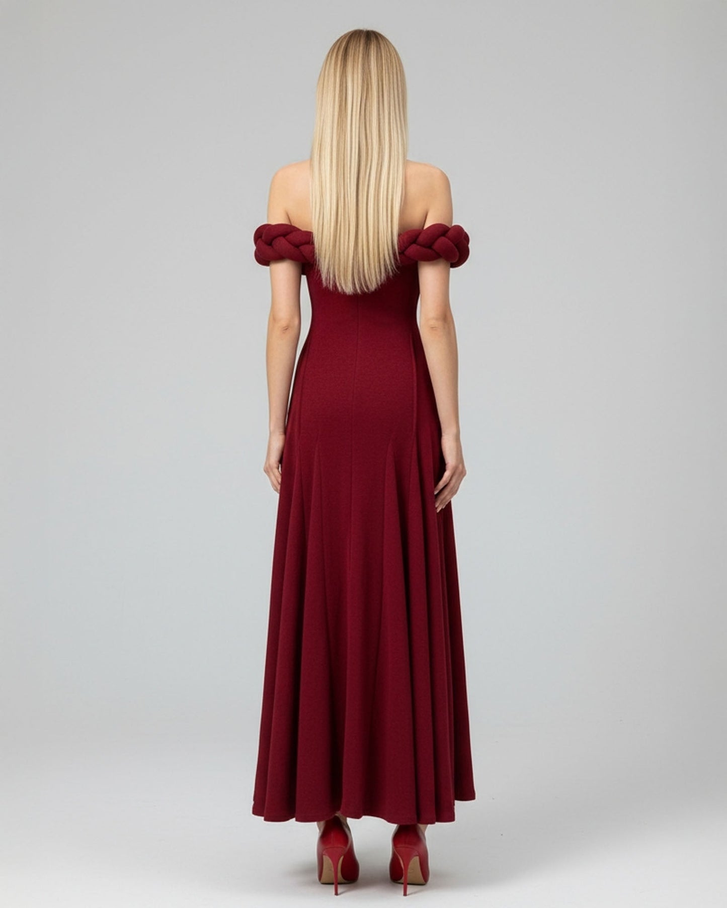 Woman wearing a burgundy off-shoulder dress on a gray background