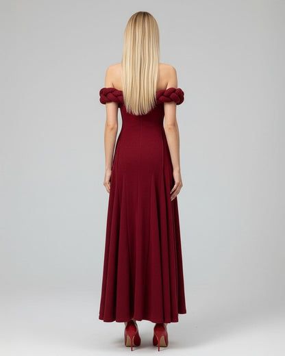 Woman wearing a burgundy off-shoulder dress on a gray background