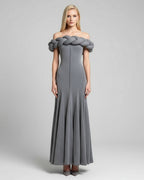 Woman wearing a gray off-shoulder dress with braided detailing on a light gray background