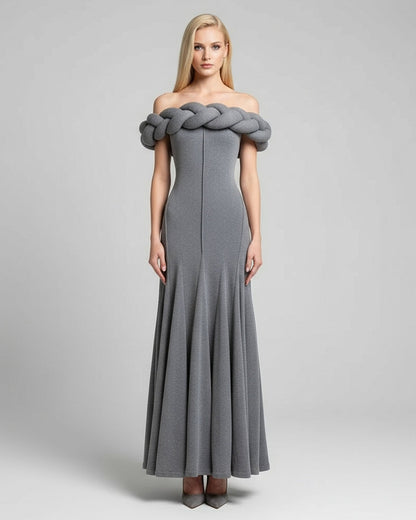 Woman wearing a gray off-shoulder dress with braided detailing on a light gray background