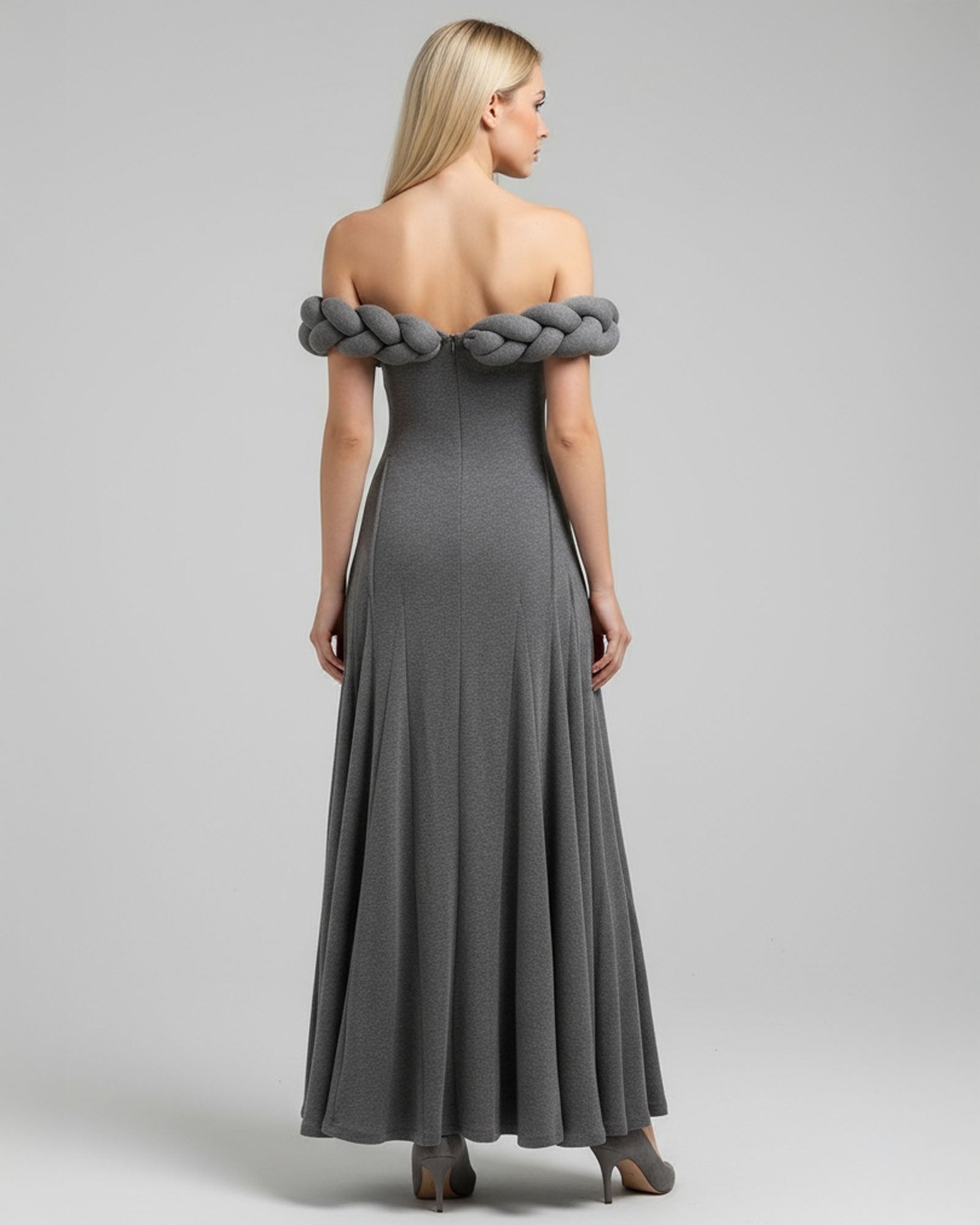 Woman wearing a gray off-shoulder dress with braided detailing on a gray background