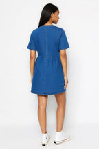 Woman wearing a blue dress against a white background
