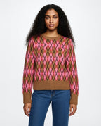 Woman wearing a brown and pink argyle sweater with blue jeans on a white background