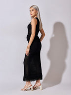 Woman wearing a black dress with feather details against a white background