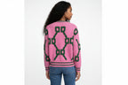 Person wearing a pink sweater with green geometric patterns on a white background